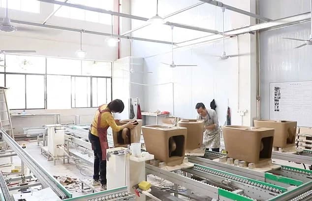 Workers repairing rough edges on smart toilet ceramic bodies.